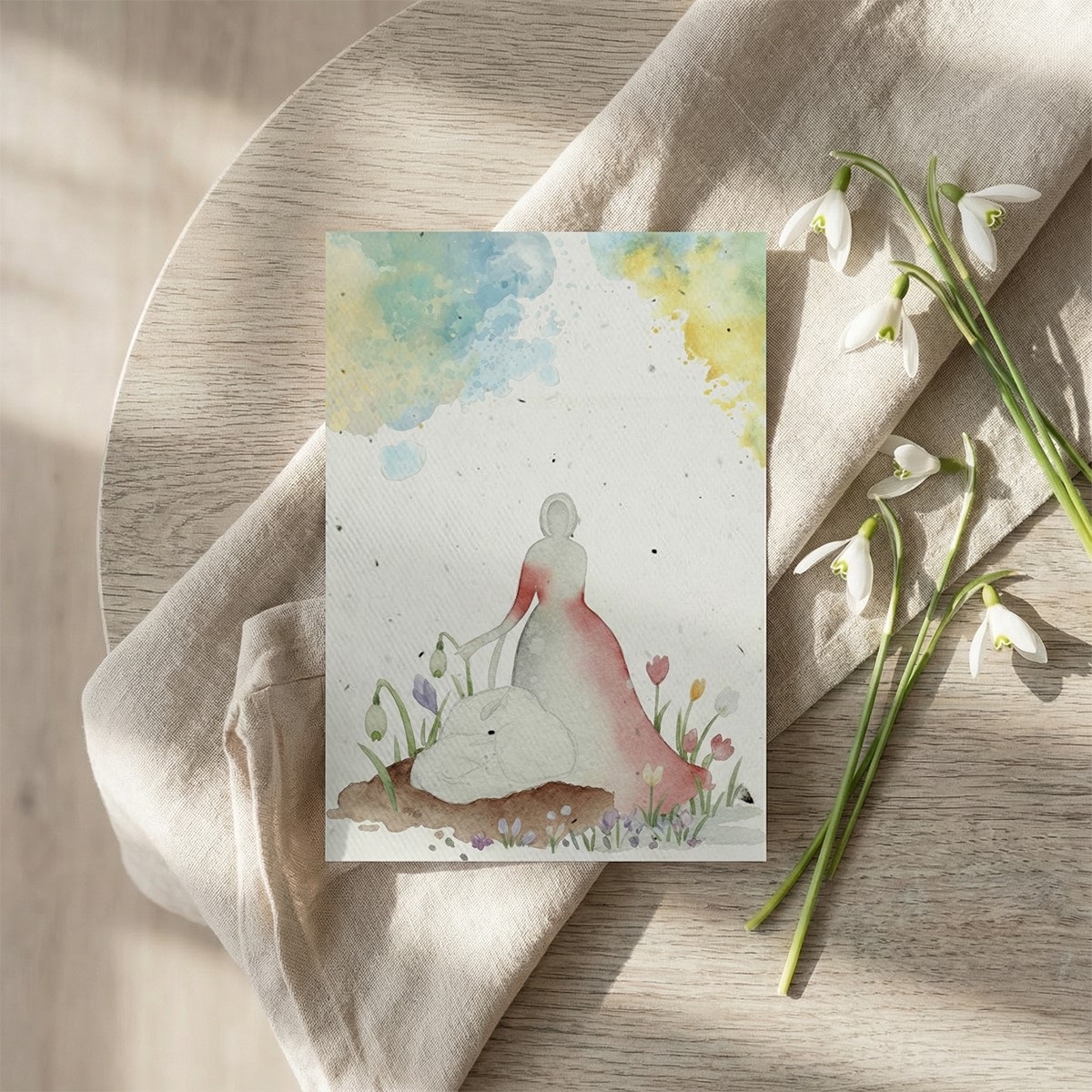 Felicitarea cu Dochia si mioara asezata pe masa de lemn cu panza de in si ghiocei